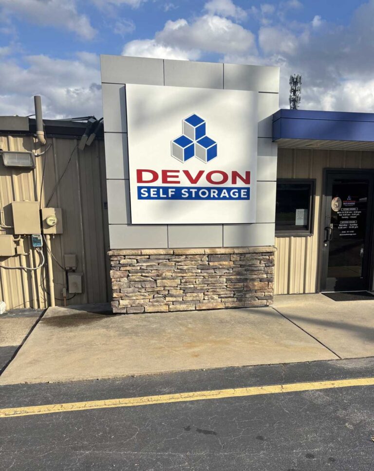 Devon Self Storage building signage with blue geometric logo on modern stone and metal facade